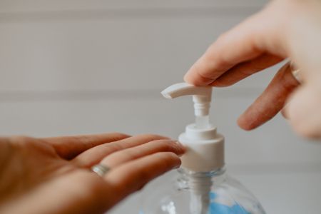 A person is holding a bottle of hand sanitizer, highlighting the significance of maintaining cleanliness and health.