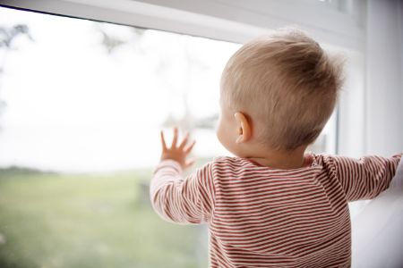 A little one looks out the window, taking in the sights and sounds of the outside world.