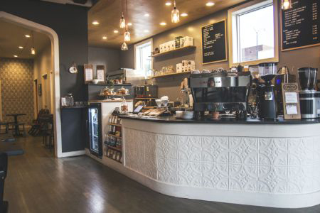 A formal coffee shop interior featuring a counter and neatly arranged tables for customers to enjoy their beverages and socialize.