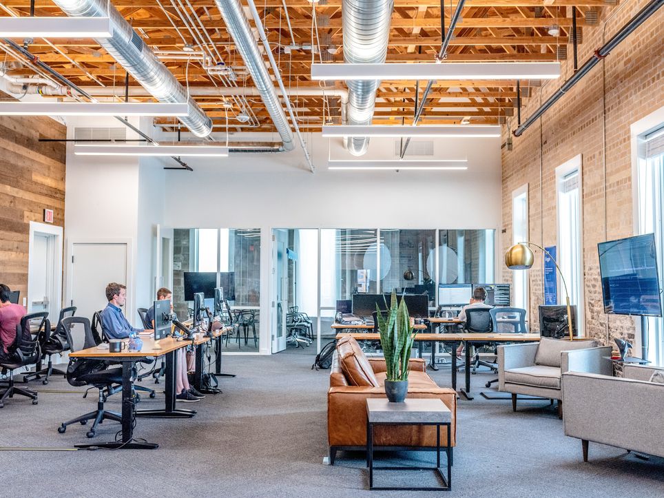 People engaged in work at desks within a spacious and collaborative open office layout. People engaged in work at desks within a spacious and collaborative open office layout.