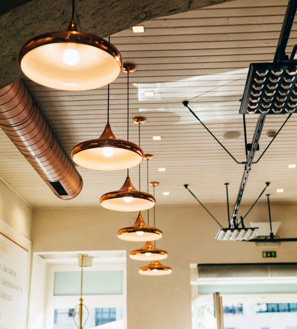 Hospitality cleaning services A restaurant with ample lighting provided by a central ceiling light and various hanging lamps throughout the room.