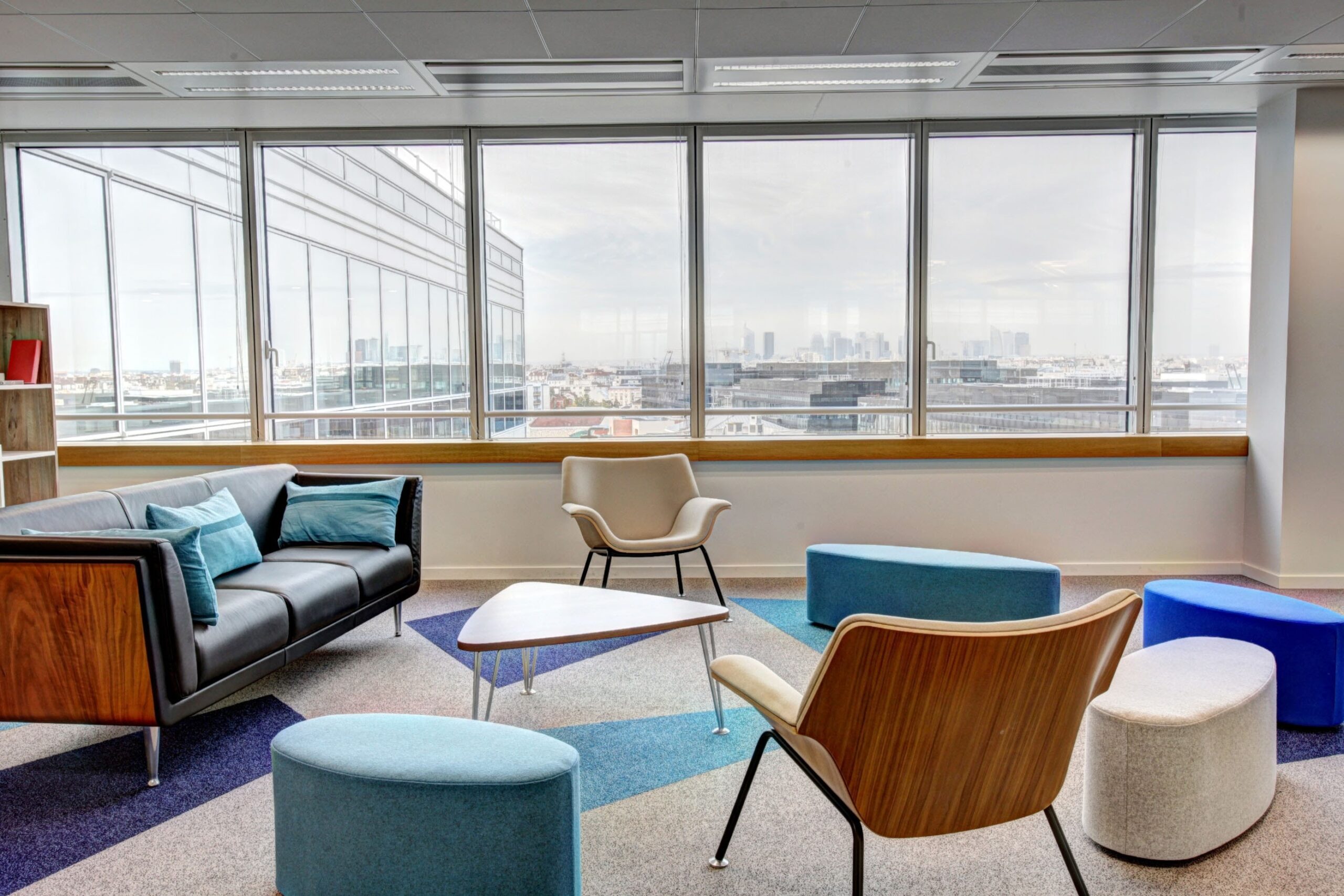 Colorful furniture adds a lively touch to this office, which benefits from ample sunlight streaming through a large window. Colorful furniture adds a lively touch to this office, which benefits from ample sunlight streaming through a large window.
