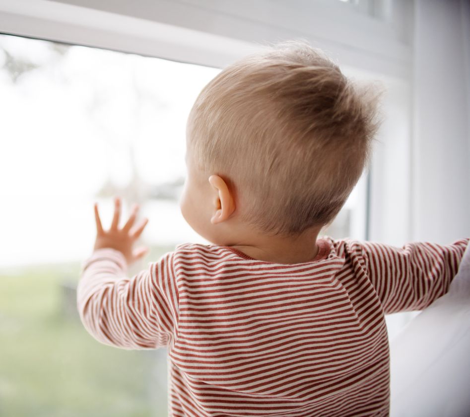 A toddler stands on tiptoe, gazing out the window with wide eyes and a sense of awe. A toddler stands on tiptoe, gazing out the window with wide eyes and a sense of awe.