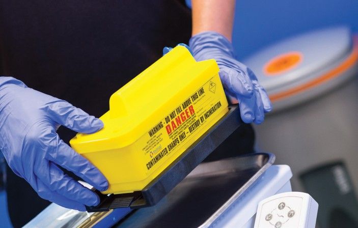 In this image, a person is seen holding a yellow box while wearing protective blue gloves. In this image, a person is seen holding a yellow box while wearing protective blue gloves.