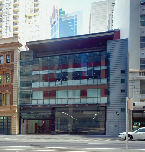 A building with a prominent glass window, accompanied by a parked car in the foreground. A building with a prominent glass window, accompanied by a parked car in the foreground.