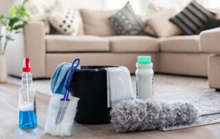 Deep cleaning equipment including spray bottle, dusting mop, and cleaning supplies placed in a modern living room.